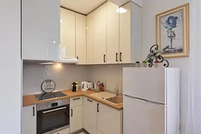 a kitchen with white cabinets and a white refrigerator at Apartman Mia Banjaluka in Banja Luka