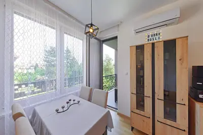 a dining room with a table and a large window at Apartman Mia Banjaluka in Banja Luka