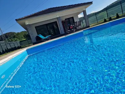 a swimming pool with blue water in front of a house at Eurouna relax in Bosanska Krupa