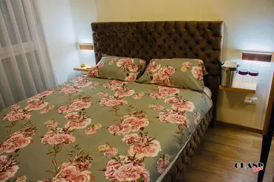 a bed with a green comforter with pink roses at GRAND LUX Mihajlo in Doboj