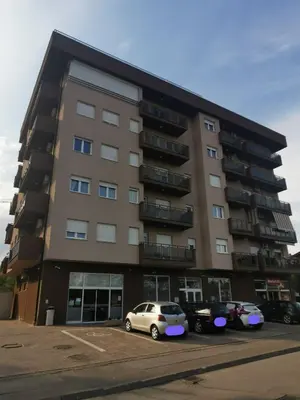a large building with cars parked in a parking lot at Apartman Vera in Banja Luka