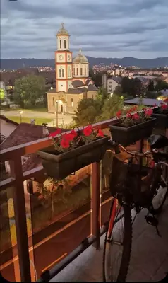 a bike parked on a fence with flowers in baskets at Apartman Vera in Banja Luka
