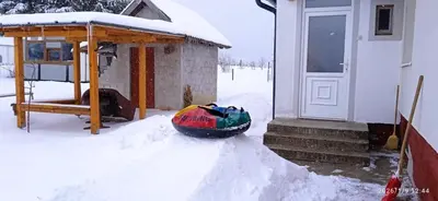 a snow covered house with a snowboard next to a door at Apartman Melani in Kupres