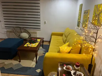 a living room with a yellow couch and a table at Apartman SI in Banja Luka