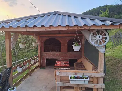 a gazebo with a waterwheel and a grill at Natural House in Visoko