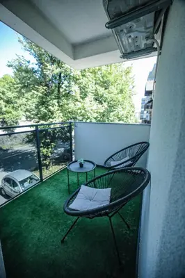 a balcony with two chairs and a table on the grass at Golemovic Comfort Stay in Banja Luka