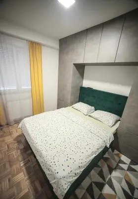 a bedroom with a bed with a green headboard at Golemovic Comfort Stay in Banja Luka