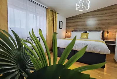 a bedroom with a large bed and a plant at Prestige Banja Luka in Banja Luka