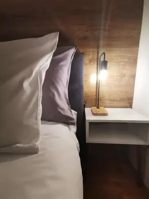 a bed with a white pillow and a nightstand with a lamp at Prestige Banja Luka in Banja Luka