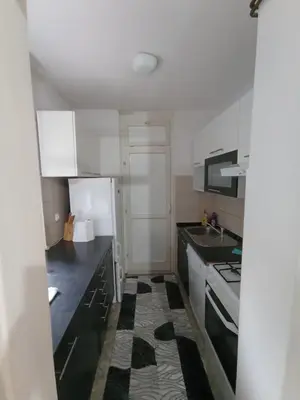 a kitchen with white cabinets and black counter tops at Apartman Dina in Bihać
