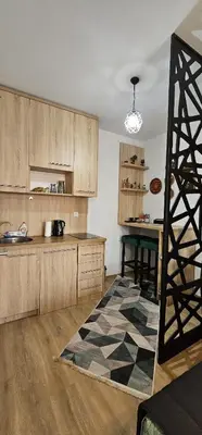 a kitchen with wooden cabinets and a table and a rug at Apartmani blue i green in Bugojno