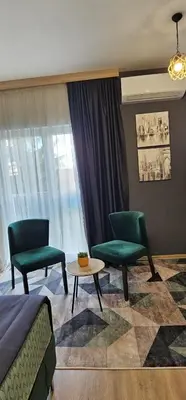 a room with two chairs and a table and a bed at Apartmani blue i green in Bugojno