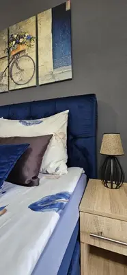 a bed with a blue headboard next to a table at Apartmani blue i green in Bugojno