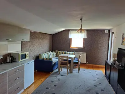 a kitchen and living room with a table and a couch at Apartman Stari Travnik in Travnik