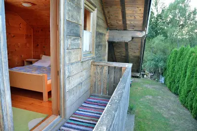 a porch of a house with a bed and a window at River house - Riječna idila in Cazin
