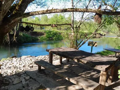a wooden bench sitting next to a river at River house - Riječna idila in Cazin