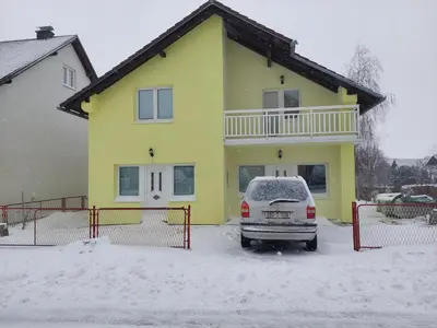 a yellow house with a car parked in the snow at Apratmani Ivić in Kupres