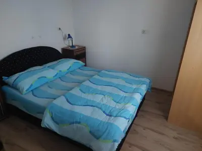a bedroom with a bed with a blue comforter at Apratmani Ivić in Kupres
