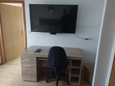 a desk with a chair and a television on a wall at Apratmani Ivić in Kupres