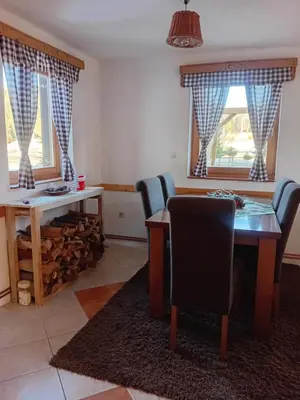 a dining room with a table and chairs and two windows at Montecasa in Travnik