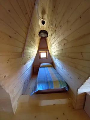 a bed in a wooden room with a small window at Montecasa in Travnik