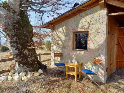 a stone cabin with a table and chairs next to a tree at Montecasa in Travnik