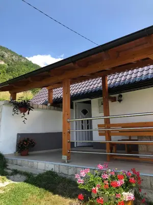 a house with a porch with flowers in the yard at Kuća za odmor Ravančić in Sopot