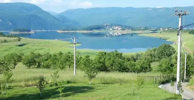 a lake in the middle of a field with mountains at Kuća za odmor Ravančić in Sopot