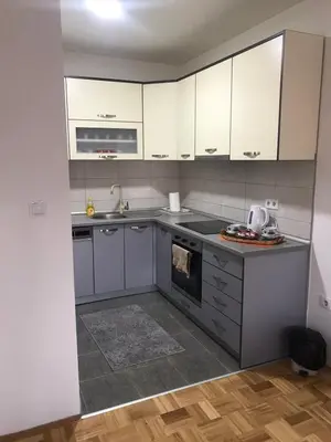 a kitchen with white cabinets and a stove top oven at Apartman Jaca in Tuzla