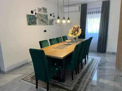 a dining room with a wooden table and green chairs at Villa Nejra in Bihać