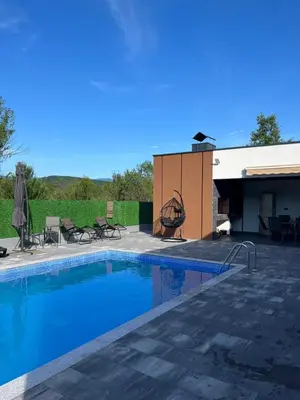 a swimming pool with a patio and a building at Villa Nejra in Bihać