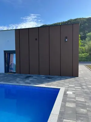 a blue swimming pool in front of a building at Villa Nejra in Bihać