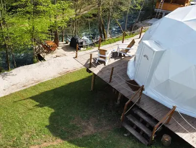 a wooden deck with chairs and a refrigerator on it at Nomad Glamping in Šipovo
