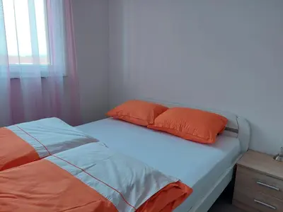 a bed with orange and blue pillows and a window at HELA Lux apartment in Modriča