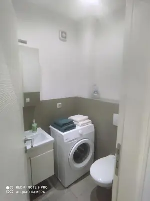 a bathroom with a washing machine and a sink at HELA Lux apartment in Modriča