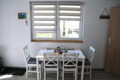 a white dining room table with chairs and a window at AURORA in Visoko