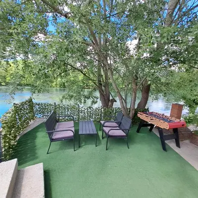 a picnic table and chairs on a lawn near the water at Kuća za odmor Unski Raj in Rudice