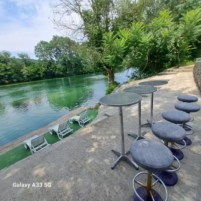 a row of tables and chairs next to a river at Kuća za odmor Unski Raj in Rudice