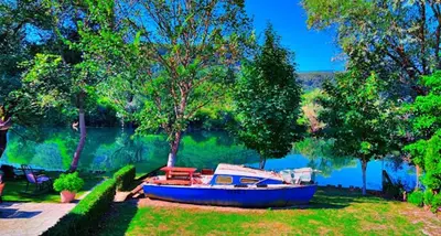 a blue boat sitting on the grass next to a lake at River Homes Bihac in Bihać