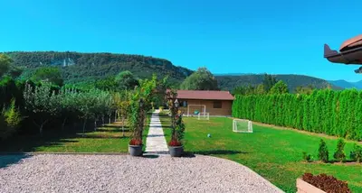 a garden with trees and a house in the background at River Homes Bihac in Bihać