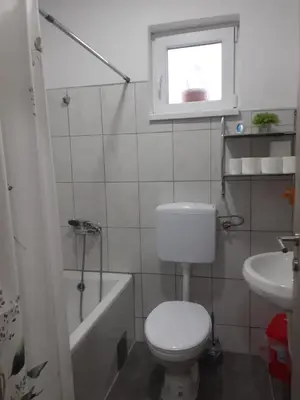 a white bathroom with a toilet and a sink at Apartman Cirkic in Sanski most