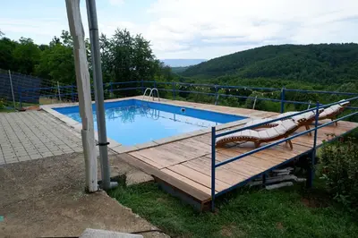 a large swimming pool with a wooden deck and a pool at Bosnian Mountain Retreat in Prijedor