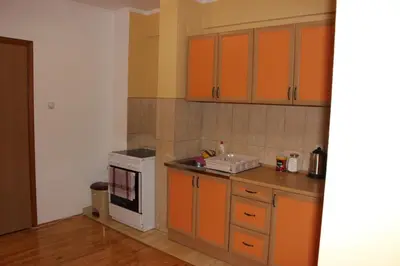 a kitchen with orange cabinets and a white stove at Apartman Romana in Doboj