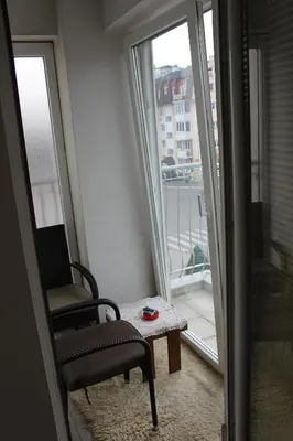 a chair and a table in a room with a balcony at Apartman Romana in Doboj