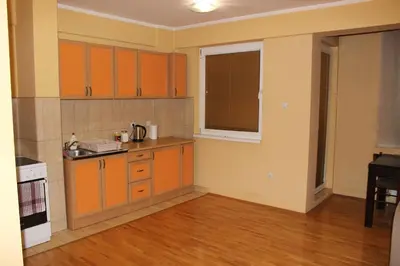 an empty kitchen with orange cabinets and a window at Apartman Romana in Doboj