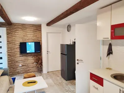 a kitchen with a refrigerator and a tv on a brick wall at S-E-N in Bosanski Novi