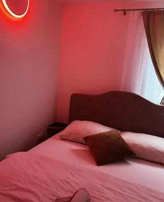 a bedroom with a bed with pink walls and a window at S-E-N in Bosanski Novi