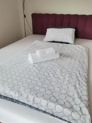a bed with a white comforter on top of it at Jelly Apartment in Visoko