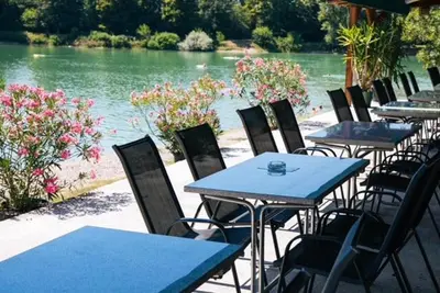 a row of tables and chairs next to a river at Jezero Laminci in Bosanska Gradiška