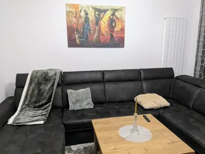 a black leather couch in a living room with a table at Apartmani Hrastik 1 in Bihać